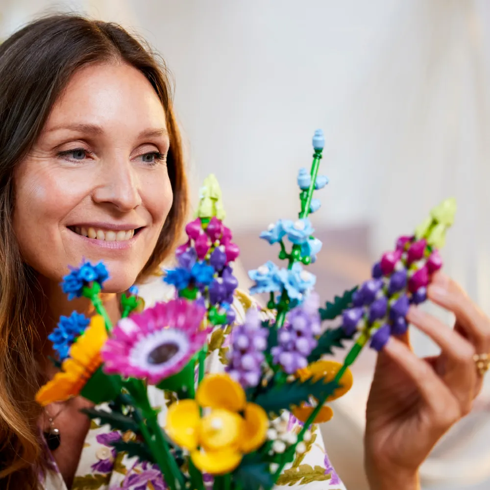 Close-up de mulher admirando as flores de LEGO do set Buquê de Flores Silvestres, enfatizando a fidelidade e a beleza duradoura.
