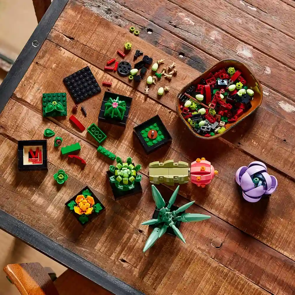Vista aérea da montagem do LEGO Suculentas 10309, mostrando os 9 módulos e peças soltas (Mindfulness e Modularidade).